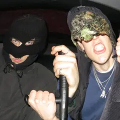 Dwóch mężczyzn w kominiarkach, jeden z nich trzyma tonfę, gotowi na bitwę w stylu tonfa rap.