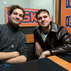 Dwóch młodych mężczyzn w studiu radiowym. Jeden w swetrze, drugi w skórzanej kurtce. Może to jeżyk raper i jego kolega?