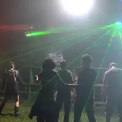 Nocna impreza z laserami, ludzie tańczą w rytm techno. Wykonawcy z lat 2000 tworzą niezapomnianą atmosferę.