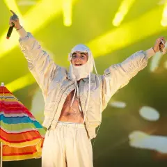 Artysta w białej stylizacji, z mikrofonem w dłoni, na tle kolorowego parasola i żółtych świateł. To musi być koncert SBM!