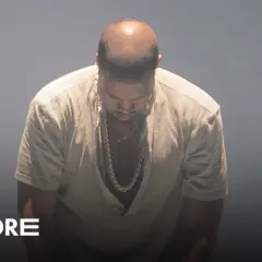 Kanye West pochyla głowę, ubrany w luźną koszulę i złoty łańcuch. W tle logo "Going. MORE" i "magazyn". Donda 2.