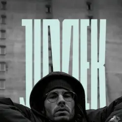 Mężczyzna w okularach i kapturze na tle bloku, z napisem "JIMEK". To część historii polskiego hip hopu.