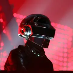 Thomas Bangalter w ikonicznym hełmie Daft Punk, na tle czerwonych świateł scenicznych.