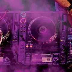DJ gra na konsoli z fioletowym dymem.