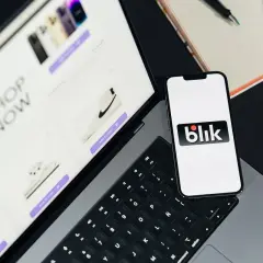 Telefon z logo Blik obok laptopa z otwartym sklepem internetowym. Szybkie zakupy z Blik!