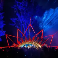 Nocny rave festival z laserami i sceną w kształcie korony. Tłum bawi się w rytm muzyki.