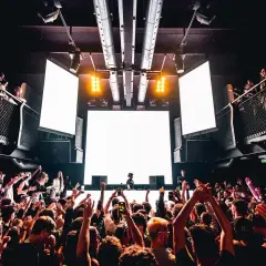 Tłum szaleje na festiwalu techno. DJ za konsolą, wielkie ekrany i światła tworzą niesamowitą atmosferę.
