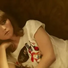 Iza Lach, młoda kobieta w białej koszulce z nadrukiem, leży na kanapie.