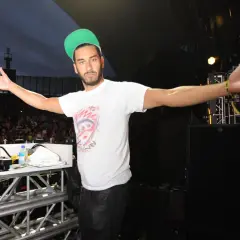 Armand Van Helden wita tłum na koncercie, rozkładając ramiona.