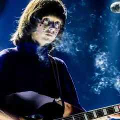 Artystka z błyszczącymi łzami na twarzy gra na gitarze podczas MTV Unplugged Polska. Dym unosi się wokół niej.