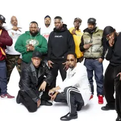 Grupa Wu-Tang Clan członkowie pozuje do zdjęcia. Wszyscy ubrani są w charakterystyczne dla hip-hopu stroje.