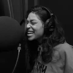Kobieta w słuchawkach nagrywa rap i trap w studiu.