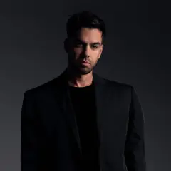 Matteo Milleri w czarnym garniturze, zamyślony, patrzy prosto w obiektyw.