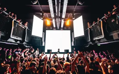 Tłum szaleje na festiwalu techno. DJ za konsolą, wielkie ekrany i światła tworzą niesamowitą atmosferę.