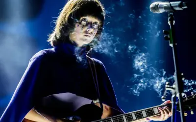 Artystka z błyszczącymi łzami na twarzy gra na gitarze podczas MTV Unplugged Polska. Dym unosi się wokół niej.