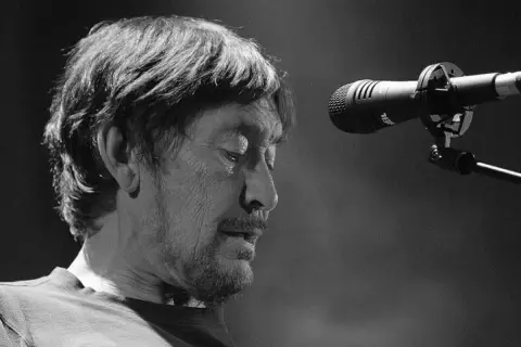 Chris Rea, zamyślony, przed mikrofonem na scenie.