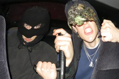 Dwóch mężczyzn w kominiarkach, jeden z nich trzyma tonfę, gotowi na bitwę w stylu tonfa rap.