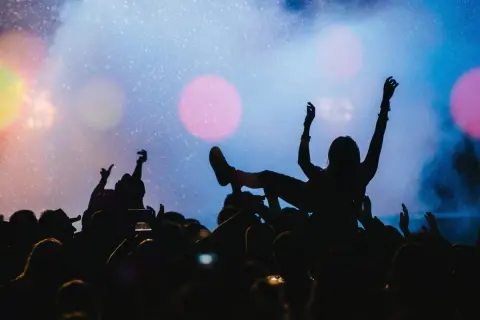 Tłumy na płock festiwal bawią się pod sceną. Jedna osoba niesiona jest na rękach, z ramionami uniesionymi w górę.