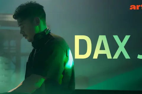 Dax J, DJ w słuchawkach, w zielonym świetle, z napisem "DAX J" i logo Arte.