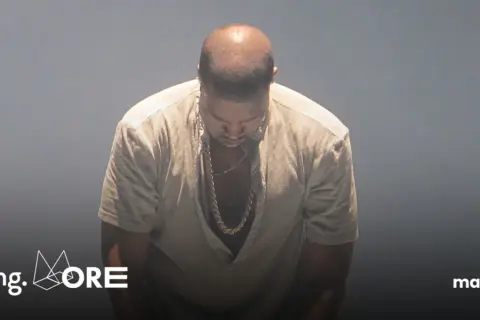 Kanye West pochyla głowę, ubrany w luźną koszulę i złoty łańcuch. W tle logo "Going. MORE" i "magazyn". Donda 2.