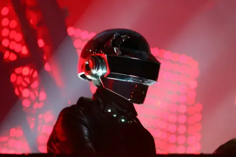 Thomas Bangalter w ikonicznym hełmie Daft Punk, na tle czerwonych świateł scenicznych.