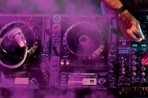 DJ gra na konsoli z fioletowym dymem.