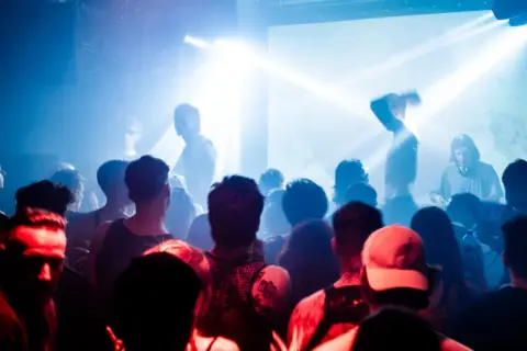 Tłum na koncercie, światła stroboskopowe, DJ Cristobal Pesce za konsolą.