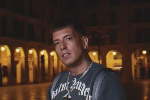 Sentino, znany z kontrowersyjnej **biografii**, w ciemnej scenerii miejskiej.
