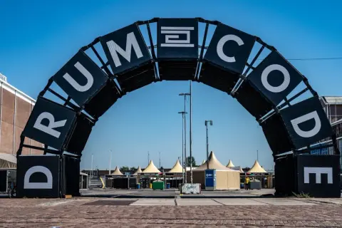 Brama festiwalowa z napisem "DRUMCODE". Wyobraź sobie, że Adam Beyer właśnie przez nią przechodzi, by rozpocząć swój set.