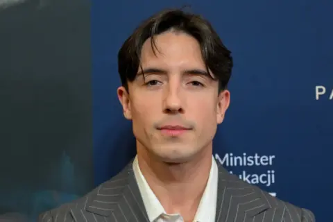 Dawid Kwiatkowski w garniturze, zapowiada swoją nową piosenkę.