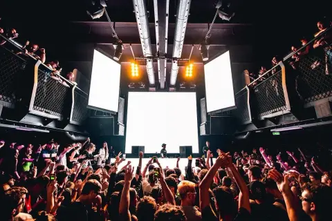 Tłum szaleje na festiwalu techno. DJ za konsolą, wielkie ekrany i światła tworzą niesamowitą atmosferę.