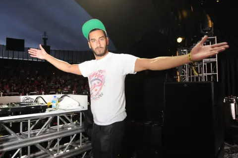 Armand Van Helden wita tłum na koncercie, rozkładając ramiona.