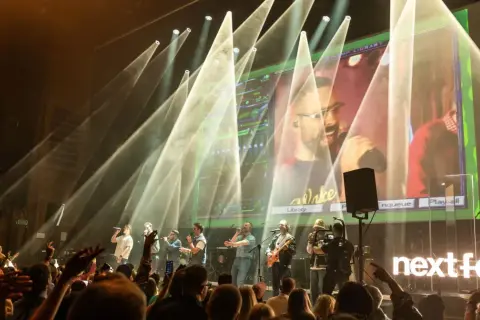 Zespół na scenie podczas koncertu na Next Fest. W tle wielki ekran z transmisją i światła.