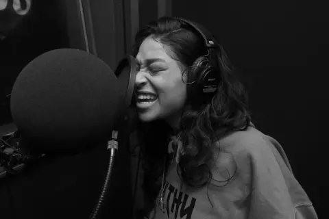 Kobieta w słuchawkach nagrywa rap i trap w studiu.