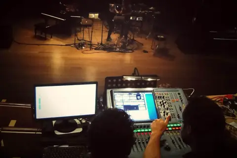 Dwie osoby przy konsolecie dźwiękowej, przygotowujące scenę do występu z elementami dub FX.