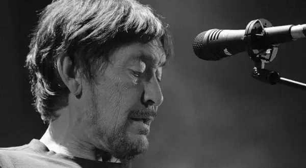 Chris Rea, zamyślony, przed mikrofonem na scenie.