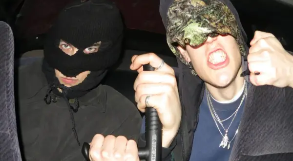 Dwóch mężczyzn w kominiarkach, jeden z nich trzyma tonfę, gotowi na bitwę w stylu tonfa rap.