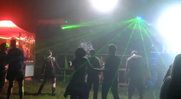 Nocna impreza z laserami, ludzie tańczą w rytm techno. Wykonawcy z lat 2000 tworzą niezapomnianą atmosferę.