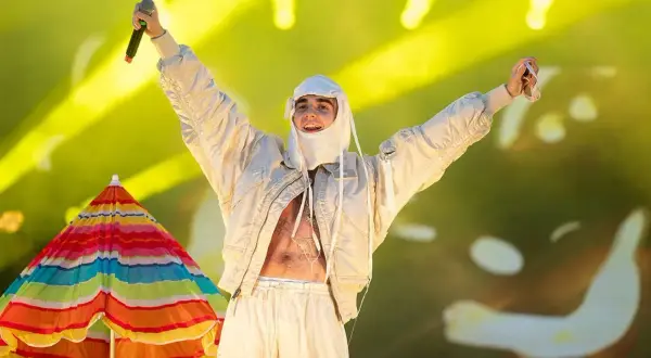 Artysta w białej stylizacji, z mikrofonem w dłoni, na tle kolorowego parasola i żółtych świateł. To musi być koncert SBM!