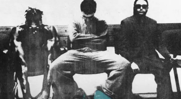 Trzech mężczyzn siedzi obok siebie. Jeden z nich ma dredy, drugi zakrywa twarz, a trzeci nosi okulary przeciwsłoneczne. Całość przypomina scenę z filmu, gdzie cbw mata jest kluczowym elementem.