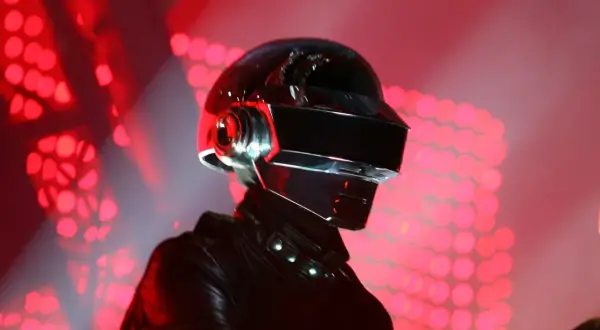 Thomas Bangalter w ikonicznym hełmie Daft Punk, na tle czerwonych świateł scenicznych.