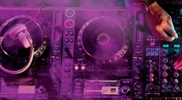 DJ gra na konsoli z fioletowym dymem.