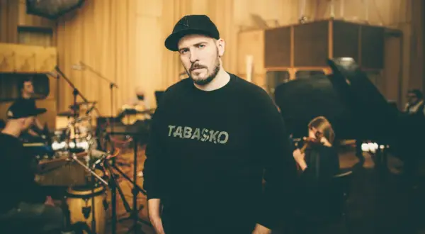 W studiu nagraniowym, w otoczeniu muzyków, stoi jeden z legend polskiego rapu, w bluzie z napisem "TABASKO".