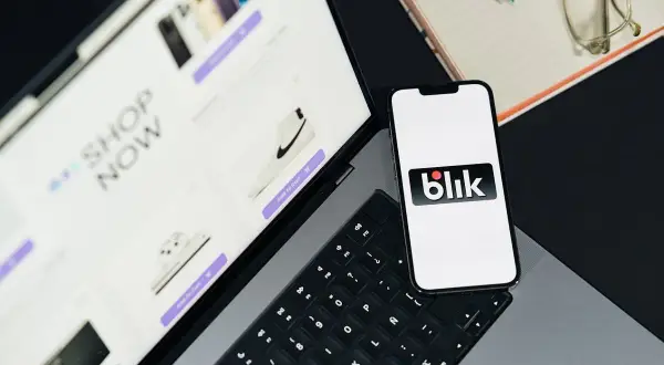 Telefon z logo Blik obok laptopa z otwartym sklepem internetowym. Szybkie zakupy z Blik!
