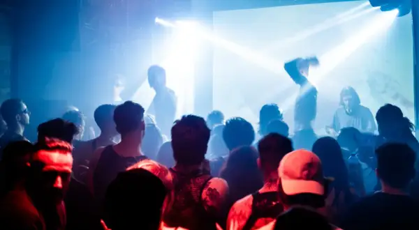 Tłum na koncercie, światła stroboskopowe, DJ Cristobal Pesce za konsolą.