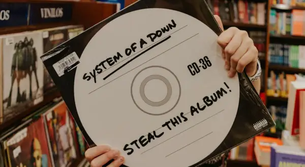 Ręce trzymają okładkę płyty System of a Down "Steal This Album!". Wybór między winyl czy CD jest tu oczywisty.