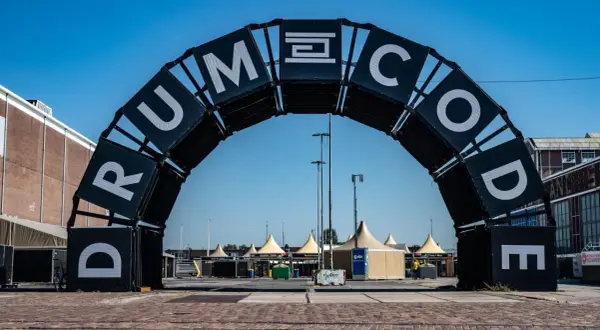 Brama festiwalowa z napisem "DRUMCODE". Wyobraź sobie, że Adam Beyer właśnie przez nią przechodzi, by rozpocząć swój set.
