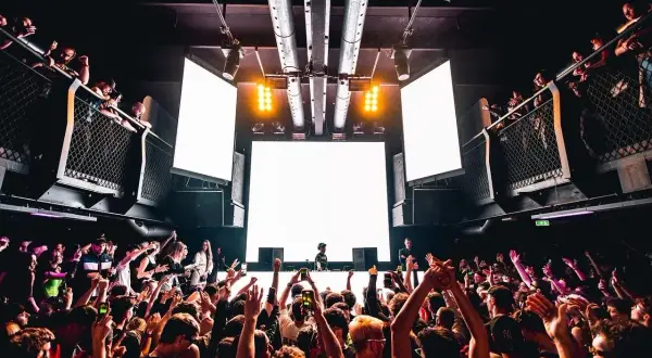 Tłum szaleje na festiwalu techno. DJ za konsolą, wielkie ekrany i światła tworzą niesamowitą atmosferę.