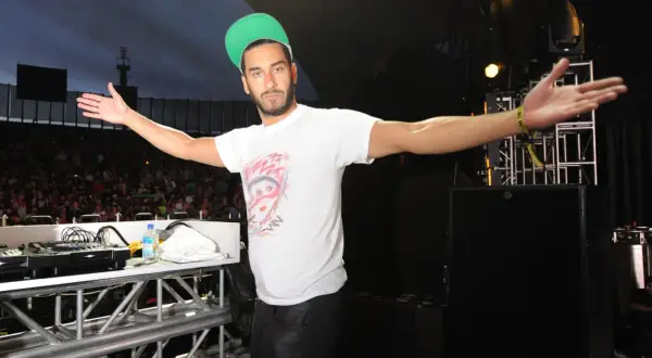 Armand Van Helden wita tłum na koncercie, rozkładając ramiona.