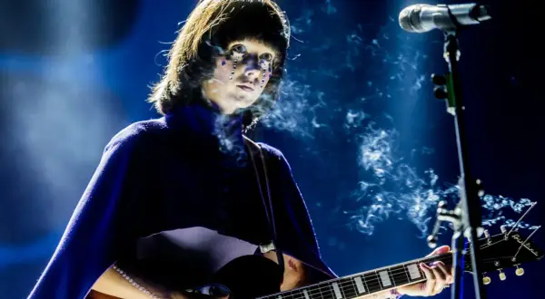 Artystka z błyszczącymi łzami na twarzy gra na gitarze podczas MTV Unplugged Polska. Dym unosi się wokół niej.